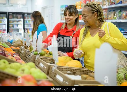 Fröhliche ethnische Frauen, die Produkte im Supermarkt auswählen Stockfoto