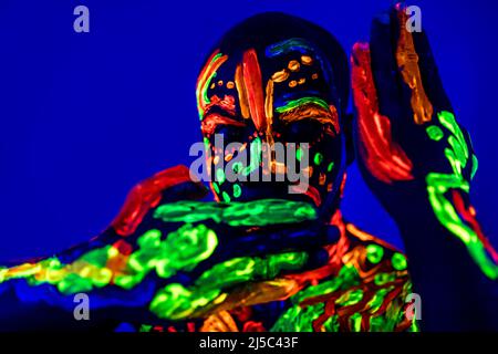 afroamerikanischer Mann posiert im Studio mit UV-Licht Stockfoto