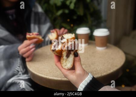 Deutsche Donuts - berliner mit Füll- und Puderzucker in weiblichen Händen. Mädchen genießen Schokolade und Marmelade Füllung Donuts Stockfoto