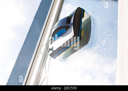 Detail eines Glasreinigungsroboters, der hinter einem Fenster agiert Stockfoto