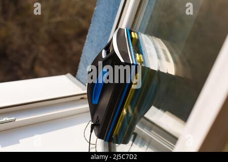 Detail eines Glasreinigungsroboters, der hinter einem Fenster agiert Stockfoto