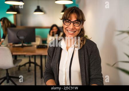 Glückliche Lateinerin im Coworking Creative Space Stockfoto