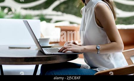 Zugeschnittenes Bild einer jungen Frau mit einem Laptop. Seitenansicht. Stockfoto