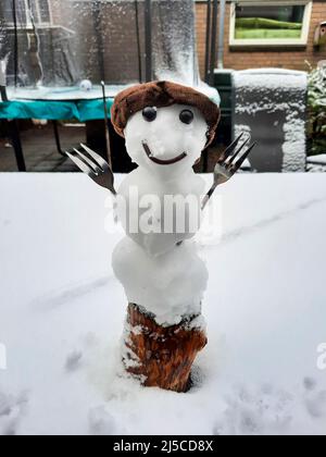 Glücklich aussehender Mini-Schneemann während einer Schneeschauer im April in den Niederlanden Nieuwerkerk Stockfoto