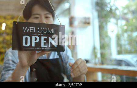 Geschäftsbesitzerin, asiatische Frau, die sich umdreht, tut mir leid, dass das Schild am Vordereingang des Glastür-Ladens geschlossen war. Stockfoto