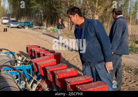 (220422) -- SHAWAN, 22. April 2022 (Xinhua) -- Ili Mehmet schaut auf die Sämaschine, während Arbeiter in seinem Baumwollfeld in Shawan, der nordwestlichen Autonomen Region Xinjiang Uygur, eine Pause von der Arbeit machen, 16. April 2022. Ili Mehmet, 50, lebt in Shawan, einem großen Baumwollanbaugebiet in Xinjiang. Während der Aussaatsaison im Frühjahr wurden die landwirtschaftlichen Arbeiten hauptsächlich von angeheuerten mechanisierten Pflanzteams durchgeführt. Doch Ili Mehmet verbringt seine Freizeit immer noch in dem 700 mu (etwa 46,7 Hektar) großen Baumwollfeld, das er mit seinem Geschäftspartner Duan Zhizhong in Auftrag gegeben hat, um neue Pflanztechniken von anderen zu erlernen. Besid Stockfoto
