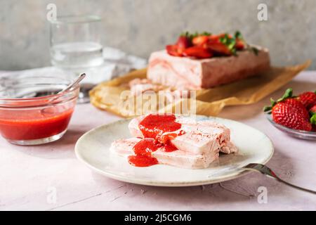 Italienisches Erdbeerdessert Semifreddo mit Sauce - kaltes Dessert wie ein Eis in Scheiben geschnitten auf dem Teller Stockfoto