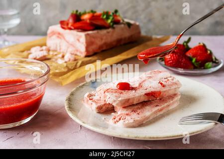 Italienisches Erdbeerdessert Semifreddo auf dem Teller mit Teelöffel Erdbeersoße gießen Stockfoto