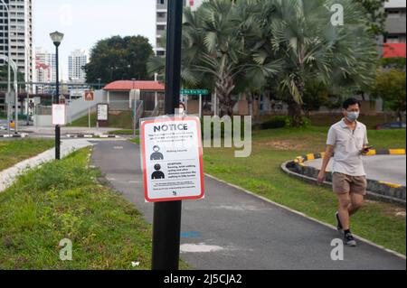 29. April 2020, Singapur, Republik Singapur, Asien - Ein Mann mit Mundschutz kommt an einem Covid-19-Schild vorbei, das verbindliche Maßnahmen zur weiteren Begrenzung der Ausbreitung des Coronavirus anzeigt. Mit Ausnahme von körperlich anspruchsvollen Aktivitäten wie Radfahren oder Joggen muss jeder bei Verlassen seines Zuhauses und im Freien oder in der Öffentlichkeit jederzeit einen Mundschutz tragen. [Automatisierte Übersetzung] Stockfoto