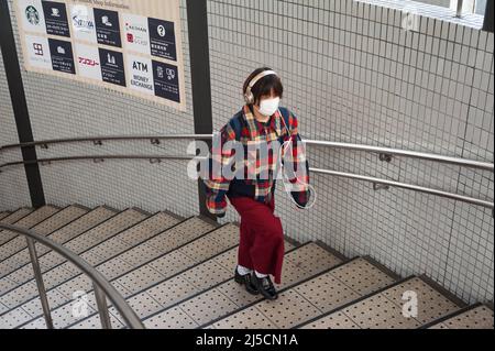 23. Dezember 2017, Kyoto, Japan, Asien - Eine junge Frau mit Mundschutz und Kopfhörern geht eine Treppe in einer U-Bahnstation in der Innenstadt hinauf. [Automatisierte Übersetzung] Stockfoto