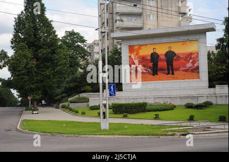 14.08.2012, Pjoengjang, Nordkorea, Asien - Eine tägliche Straßenszene zeigt eine Gedenktafel mit den Porträts der beiden ehemaligen Führer Kim Il-sung und Kim Jong-il am Straßenrand. Der Personenkult um die beiden verstorbenen Präsidenten ist immer noch allgegenwärtig und landesweit trifft man auf ihre Bilder und Statuen. [Automatisierte Übersetzung] Stockfoto