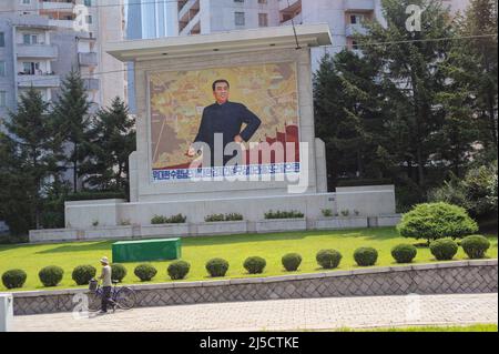 08.08.2012, Pjoengjang, Nordkorea, Asien - Eine tägliche Straßenszene zeigt eine Gedenktafel mit dem Porträt von Kim Il-sung und Wohnhäusern im Hintergrund. Der Personenkult um die beiden ehemaligen Führer ist immer noch allgegenwärtig und ihre Bilder und Statuen erscheinen überall im Land. [Automatisierte Übersetzung] Stockfoto