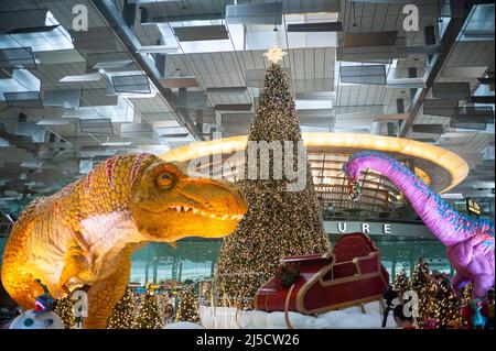 08. Dezember 2020, Singapur, Republik Singapur, Asien - Dinosaurier, Ein Schlitten und ein Weihnachtsbaum dienen im Dino Wanderland als Weihnachtsdekoration und Fotoruckentwürfe für Besucher und Flugreisende in der Abfluglounge im Terminal 3 des Changi International Airport inmitten der globalen Coronavirus-Pandemie (Covid-19). [Automatisierte Übersetzung] Stockfoto