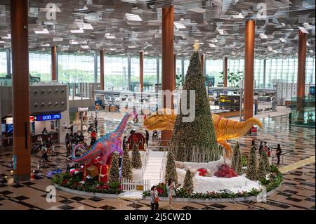08. Dezember 2020, Singapur, Republik Singapur, Asien - Dinosaurier, Ein Schlitten und ein Weihnachtsbaum dienen im Dino Wanderland als Weihnachtsdekoration und Fotoruckentwürfe für Besucher und Flugreisende in der Abfluglounge im Terminal 3 des Changi International Airport inmitten der globalen Coronavirus-Pandemie (Covid-19). [Automatisierte Übersetzung] Stockfoto