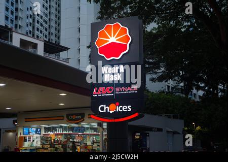 14. Dezember 2020, Singapur, Republik Singapur, Asien - an einer Tankstelle in einem Wohngebiet weist ein beleuchtetes Schild mit der Aufschrift „Wear A Mask“ darauf hin, dass in der Regel an öffentlichen Orten Masken benötigt werden, um eine weitere Ausbreitung des Coronavirus (Covid-19) während der globalen Coronapandemie zu verhindern. [Automatisierte Übersetzung] Stockfoto