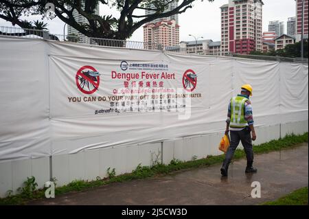 14. Dezember 2020, Singapur, Republik Singapur, Asien - Ein Arbeiter geht an einer Baustelle in einer Wohngegend vorbei, wo ein großes Banner auf dem Bauzaun vor der Gefahr warnt, dass sich Dengue-Fieber von Mücken ausbreitet und anzieht, Da sie stehendes Wasser wie das auf Baustellen gefundene als mögliche Brutplätze nutzen. [Automatisierte Übersetzung] Stockfoto