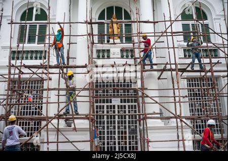 21. Dezember 2020, Singapur, Republik Singapur, Asien - in Zeiten der anhaltenden Koronakrise (Covid-19) demontieren eine Gruppe südasiatischer Arbeiter nach Abschluss der Renovierungsarbeiten ein Holzgerüst vor einer Kirche im Stadtzentrum. Die Mehrheit der Bauarbeiter sind Wanderarbeiter aus Indien, Bangladesch und Nepal, die in kollektivem Wohnraum zusammenleben. [Automatisierte Übersetzung] Stockfoto