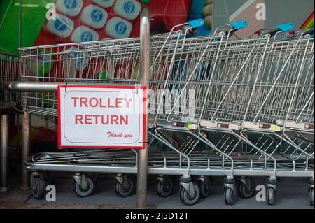 18.04.2021, Singapur, Republik Singapur, Asien - Eine Reihe von Einkaufswagen, die vor einem Supermarkt der Kette Fairprice ineinander geschoben wurden, und ein Schild mit der Aufschrift Einkaufswagen Rueckgabe (Trolley Return). [Automatisierte Übersetzung] Stockfoto