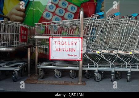 18.04.2021, Singapur, Republik Singapur, Asien - Eine Reihe von Einkaufswagen, die vor einem Supermarkt der Kette Fairprice ineinander geschoben wurden, und ein Schild mit der Aufschrift Einkaufswagen Rueckgabe (Trolley Return). [Automatisierte Übersetzung] Stockfoto