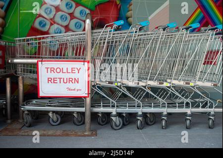 18.04.2021, Singapur, Republik Singapur, Asien - Eine Reihe von Einkaufswagen, die vor einem Supermarkt der Kette Fairprice ineinander geschoben wurden, und ein Schild mit der Aufschrift Einkaufswagen Rueckgabe (Trolley Return). [Automatisierte Übersetzung] Stockfoto