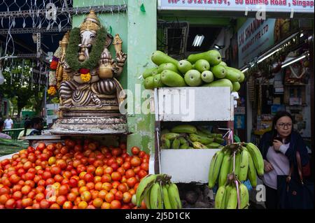 10. Mai 2019, Singapur, Republik Singapur, Asien - Eine Frau geht an einem Lebensmittelgeschäft im Viertel Little India vorbei, in dem eine Hindu-Statue von Ganesha an der Außenseite und ein kleiner Schrein angebracht sind. [Automatisierte Übersetzung] Stockfoto