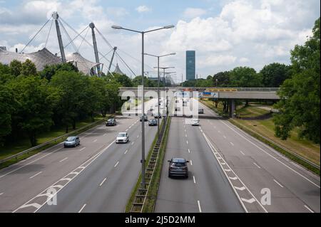 06/23/2019, München, Bayern, Deutschland, Europa - Stadtverkehr auf der Bundesstraße Georg-Brauchle-Ring, Teil des Mittleren Rings mit dem Dach des Olympiastadions und der Hochhaushochburg München im Hintergrund. [Automatisierte Übersetzung] Stockfoto