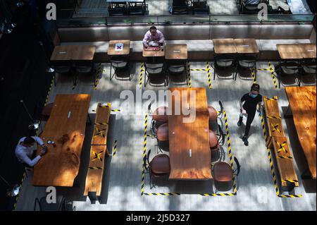 15. September 2021, Singapur, Republik Singapur, Asien - Menschen essen in einem Restaurant in einem Einkaufszentrum von Raffles Place, wo Tische und Bänke mit Klebeband markiert sind, um die Ausbreitung des hochansteckenden Coronavirus in öffentlichen Bereichen durch sichere Entfernungsmaßnahmen zu begrenzen. Die Zahl der neuen lokalen Infektionen mit dem COVID-19-Virus ist mit mehr als 800 Infektionen die höchste seit April letzten Jahres. Inzwischen wurden 82 der Bevölkerung doppelt geimpft. [Automatisierte Übersetzung] Stockfoto