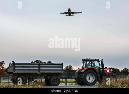 Schönefeld, 03.11.2021 - kurz vor der Landung am Flughafen Berlin Brandenburg fliegt ein Flugzeug über eine Straße, auf der ein Traktor fährt. Die Flughafengesellschaft Berlin Brandenburg, FBB, machte 2020 einen Verlust von einer Milliarde Euro aus. [Automatisierte Übersetzung] Stockfoto