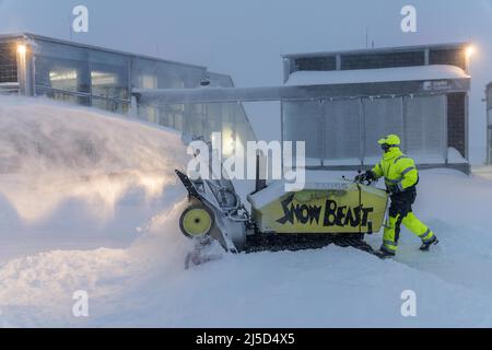 Ein Mitarbeiter der Zugspitzbahn räumt morgens, Winter, Zugspitze, Schnee, Bayern mit einem Schneegebläse die Terrasse auf dem Gipfel ab Stockfoto