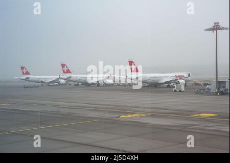 14. Dezember 2021, Zürich, Schweiz, Europa - die Airbus A220-Passagierflugzeuge von Swiss Airlines parken an ihren Standpositionen auf dem Vorfeld am Flughafen Zürich. Swiss ist Mitglied der Luftfahrtallianz Star Alliance, einem internationalen Netzwerk von Fluggesellschaften. [Automatisierte Übersetzung] Stockfoto