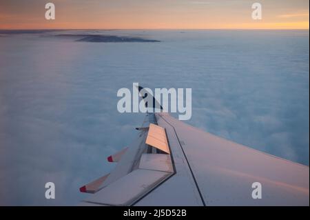 14. Dezember 2021, Zürich, Schweiz, Europa - Luftaufnahme auf dem Flug von Singapore Airlines von Singapur nach Zürich am frühen Morgen mit Blick aus dem Flugzeug auf die Flügel und die Wolkendecke unten. [Automatisierte Übersetzung] Stockfoto