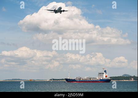 29. November 2021, Singapur, Republik Singapur, Asien - Ein Frachtflugzeug der Qatar Airways Cargo Boeing 777-200F auf dem Weg zum Changi International Airport. Unten segelt der Chemie- und Öltanker Eagle Garnet auf See entlang der Küste. [Automatisierte Übersetzung] Stockfoto