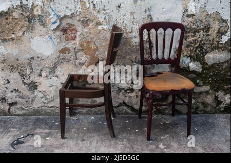 06/14/2021, Singapur, Republik Singapur, Asien - zwei alte und weggeworfene Stühle stehen am Straßenrand vor einer Hauswand im Viertel Little India. [Automatisierte Übersetzung] Stockfoto