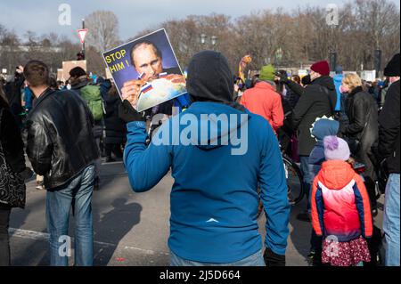 '27.02.2022, Berlin, Deutschland, Europa - Ein Demonstrator hält ein Protestschild mit einem Foto von Putin vor der Siegessäule am zentralen Platz Grosser Stern hoch. In Berlin protestieren mehrere hunderttausend Menschen für den Frieden in Europa und gegen den vom russischen Präsidenten Putin initiierten illegalen Angriffskrieg Russlands in der Ukraine. Die große Demonstration im Bezirk Tiergarten erstreckt sich von der Siegessäule entlang der Straße des 17. Juni bis zum Brandenburger Tor und findet unter dem Motto "'Stoppt den Krieg. Frieden für die Ukraine und ganz Europa“. [Automatisierte Übersetzung]' Stockfoto