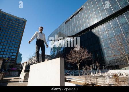 '03/12/2022, Berlin, Deutschland, Europa - die Skulptur ''Balanceakt'' ist ein Werk des deutschen Bildhauers Stephan Balkenhol und steht vor dem Axel Springer Wolkenkratzer und dem Neubau an der Ecke Axel-Springer-Straße und Zimmerstraße im Berliner Bezirk Kreuzberg. Die Arbeit besteht aus einem Mann mit schwarzer Hose und einem weißen Hemd, der auf einem Stück der Berliner Mauer balanciert, sowie elf Originalteilen der Mauer, die um die Figur platziert sind. Das Denkmal soll an die deutsche Wiedervereinigung und insbesondere den Fall der Mauer erinnern. [Automatisierte Übersetzung]' Stockfoto