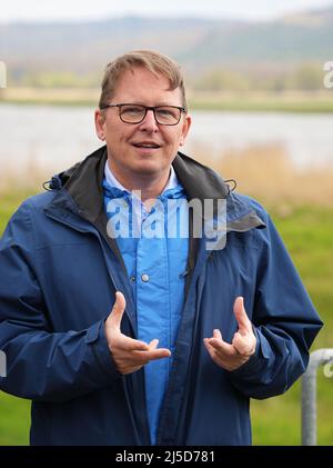 Brandenburg, Deutschland. 22. April 2022. 22. April 2022, Brandenburg, Angermünde/OT Criewen: NABU-Präsident Jörg-Andreas Krüger spricht im Nationalpark Unterodertal nahe dem Aussichtsturm Stützkow am Ufer der oder. Das NABU-Zentrum Blumberger Mühle hat zusammen mit dem Leibniz-Institut für Gewässerökologie und Binnenfischerei (IGB) und dem Teichmanagement Blumberger Teiche rund 500 junge Baltische Störe in die oder entlassen. Seit fünfzehn Jahren findet im Grenzfluss Stör statt und versucht, Stör in den Flüssen in Deutschland wieder einzuführen Stockfoto