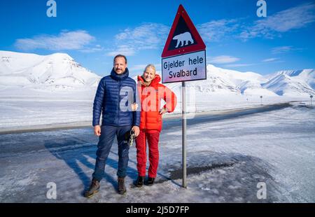 Longyearbyen, Svalbard 20220421.Kronprinz Haakon und Kronprinzessin Mette-Marit bei einem Schild, das vor Eisbären während der Reise des Kronprinzenpaares nach Svalbard warnt. Foto: Ole Berg-Rusten / NTB Stockfoto