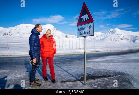 Longyearbyen, Svalbard 20220421.Kronprinz Haakon und Kronprinzessin Mette-Marit bei einem Schild, das vor Eisbären während der Reise des Kronprinzenpaares nach Svalbard warnt. Foto: Ole Berg-Rusten / NTB Stockfoto