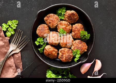 Hausgemachte Koteletts aus Hackfleisch in einer Pfanne auf schwarzem Hintergrund. Draufsicht, flach liegend Stockfoto