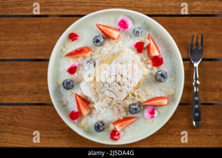Meringuerolle mit Erdbeeren, Blaubeeren, Himbeeren und Preiselbeeren. Dessert mit frischen Beeren auf dem Tisch dekoriert. Stockfoto
