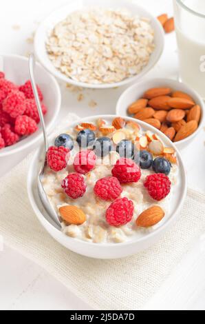 Haferbrei mit Himbeeren, Heidelbeeren und Nüssen in einer Schüssel Stockfoto