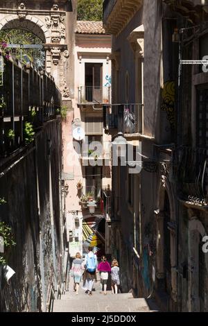 Menschen, darunter eine Touristenfamilie, steigen auf der Via Penninello, Stadt Catania, Sizilien, versunken hinab. Italien. Von der Via Crociferi aus gesehen. (129) Stockfoto