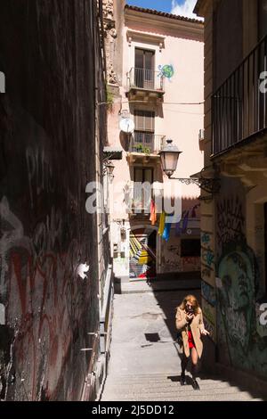 Junge Frau im Gespräch am Telefon / Handy / Telefon / zu Fuß auf versunkene aufsteigende Treppe auf der Via Penninello, Stadt Catania, Sizilien. Italien. Von der Via Crociferi aus gesehen. (129) Stockfoto