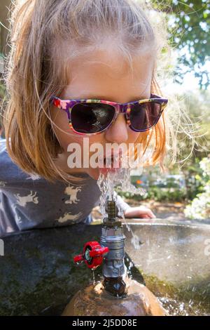 Junges Mädchen mit einem Getränk von Wasser / Trinken aus einem Durstlöschendes öffentlichen Brunnen draußen, in einem Stadtpark, in Catania, Sizilien. Italien. (129) Stockfoto