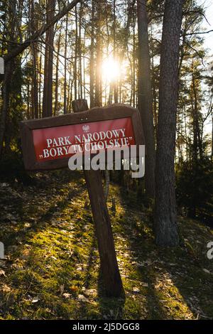 Wodden-Schild mit Schriftzug National Park Bory Tucholskie steht in der Mitte des Waldes. Schild in dunkelbrauner Farbe und rotem Hintergrund in Holz Stockfoto