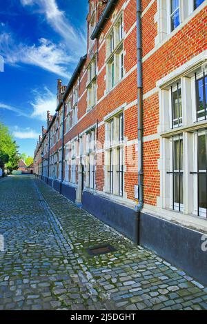 Lier (Begijnhof, Grachtkant), Belgien - April 9. 2022: Blick auf brabant-Stil Häuserblock, roten Ziegel und Specksteinverkleidungen aus weichem weißen Stein, Kopfsteinpflaster Stockfoto