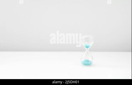 Sandglas auf hellem Licht, Sandglas mit blauem Sand auf weißem Hintergrund Stockfoto