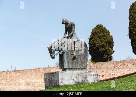 Bronzestatue eines Ritters auf dem Pferderücken vor der Basilika des Heiligen Franziskus von Assisi. Statue des besiegten Ritters. Stockfoto