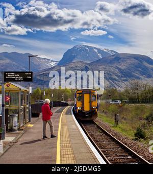 PASSAGIERE DER WEST HIGHLAND-EISENBAHNLINIE VON FORT WILLIAM SCOTLAND SCOTRAIL WARTEN AUF DEN ZUG, DER AM BAHNHOF VON BANAVIE ANKOMMT UND EINEN BLICK AUF BEN NEVIS BIETET Stockfoto