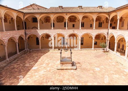 Interner Kreuzgang der Basilika des Heiligen Franziskus von Assisi. Innenhof mit Brunnen in der Kirche von San Francesco in Assisi, Umbrien, Italien. Stockfoto